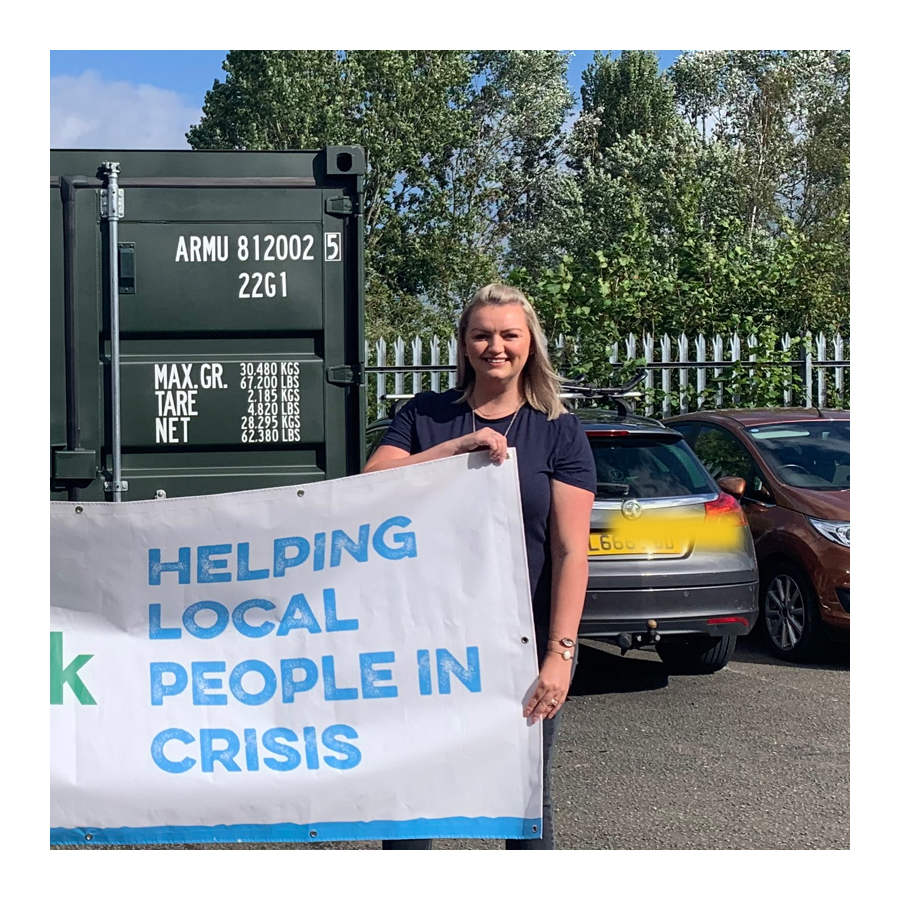 Woman holding sign that says helping local people in crisis