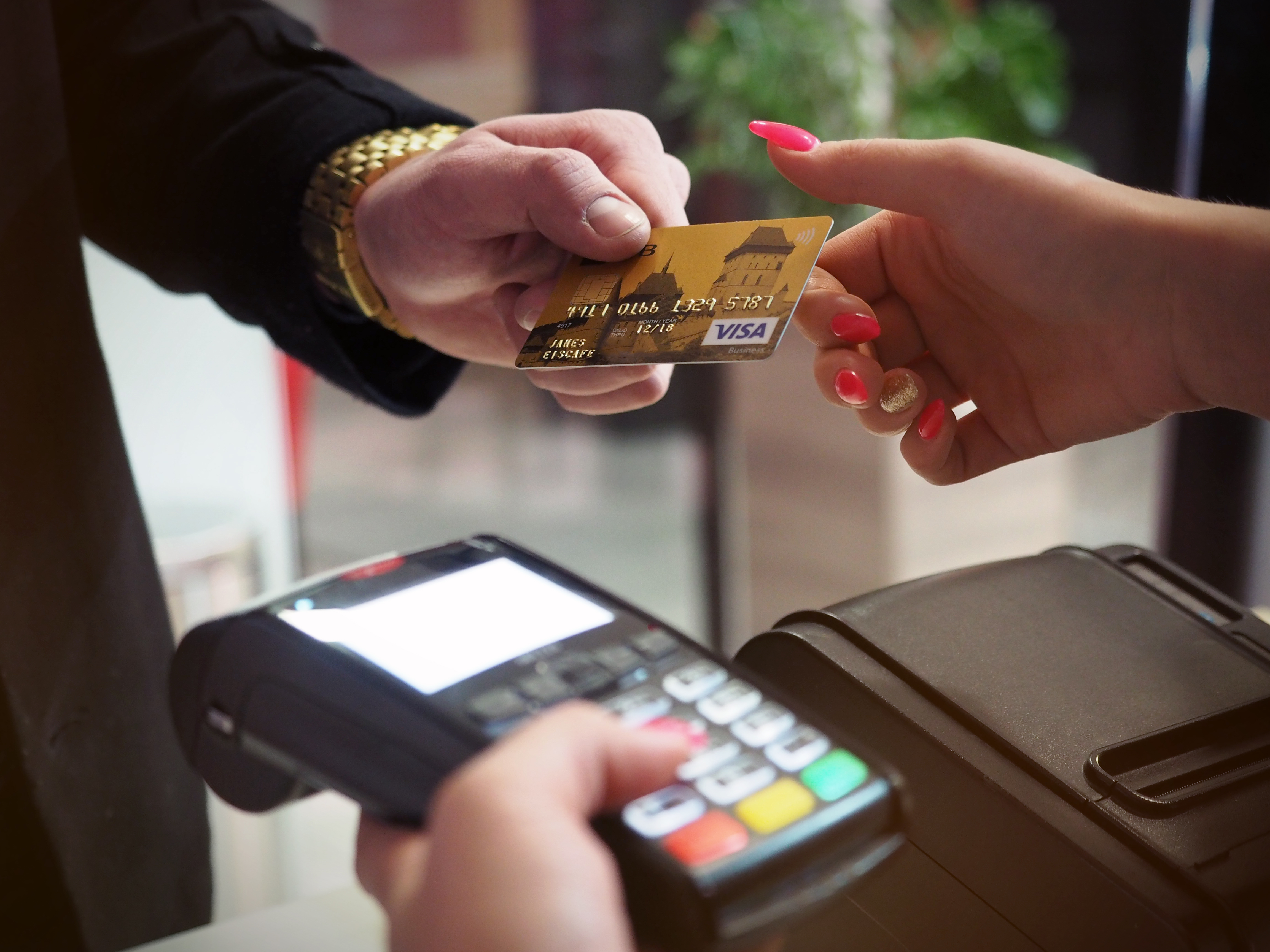 Man passing a credit card to a lady with a contactless payment device